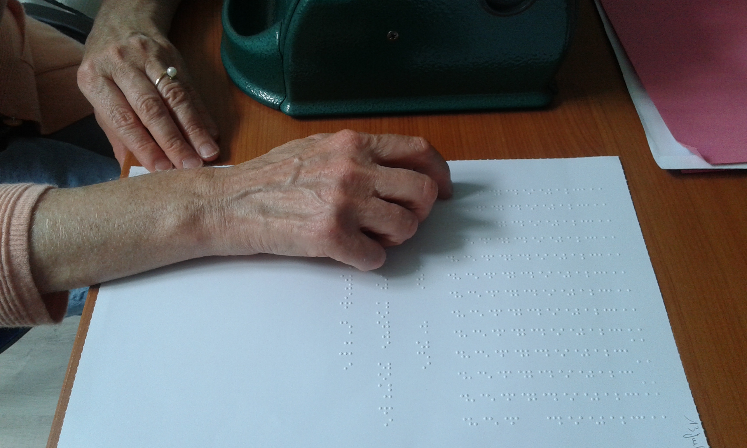 Main parcourant un texte en Braille